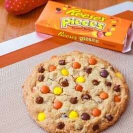 one giant peanut butter Reese's Pieces cookie on a silpat baking mat