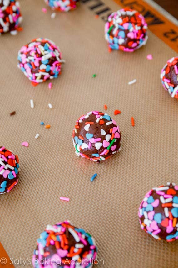 chocolate cake mix cookie dough balls rolled in sprinkles on a silpat baking mat