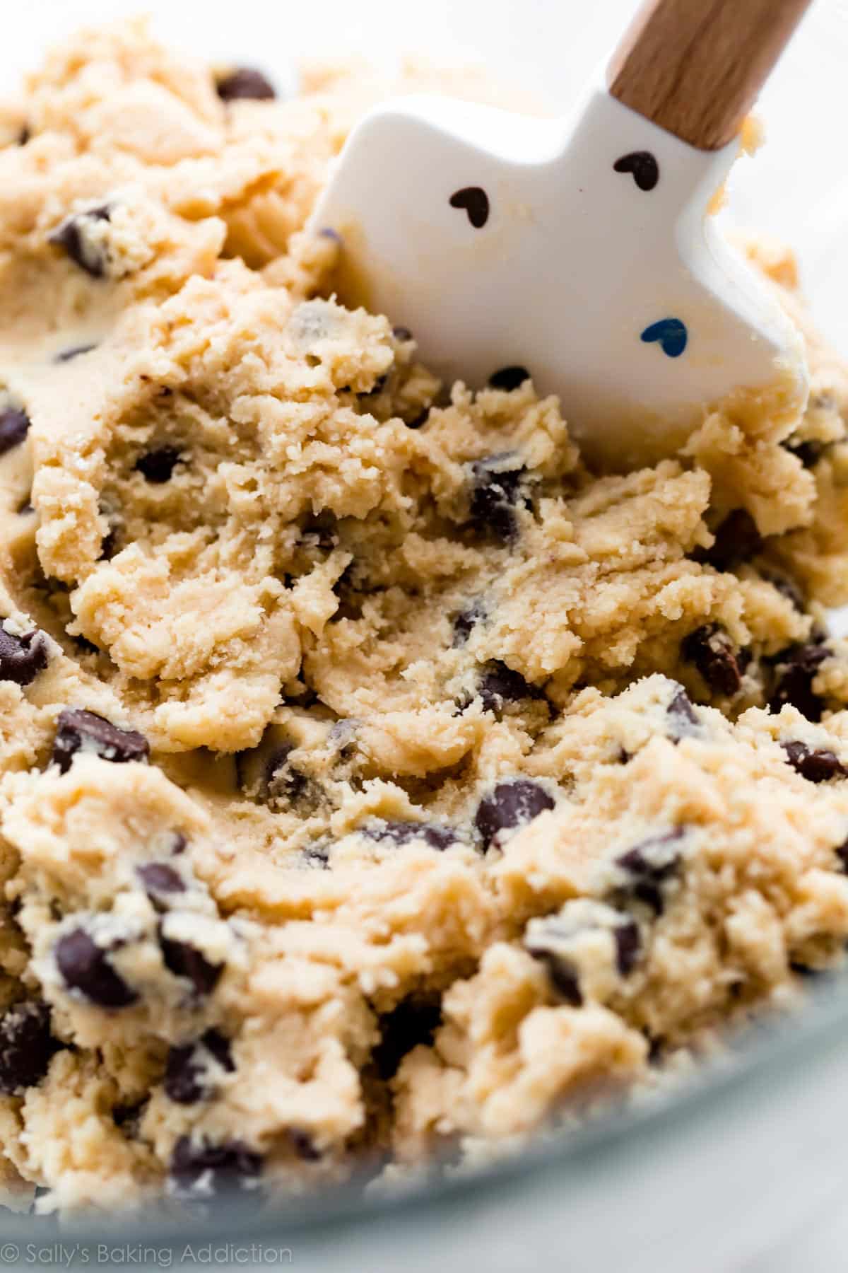 chocolate chip cookie dough in a glass bowl with spatula