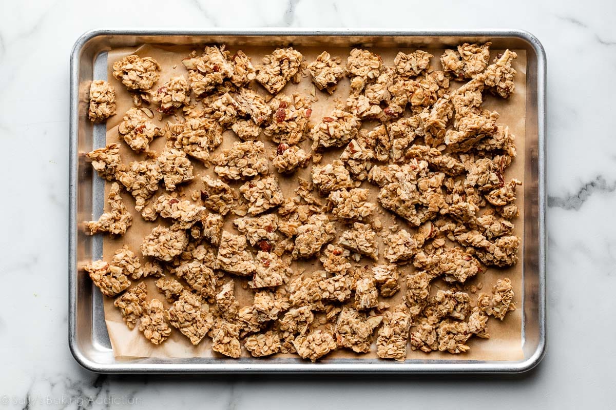 granola clusters spread on lined baking sheet.