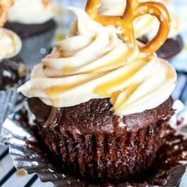 chocolate cupcakes topped with salted caramel frosting and a pretzel on a cooling rack