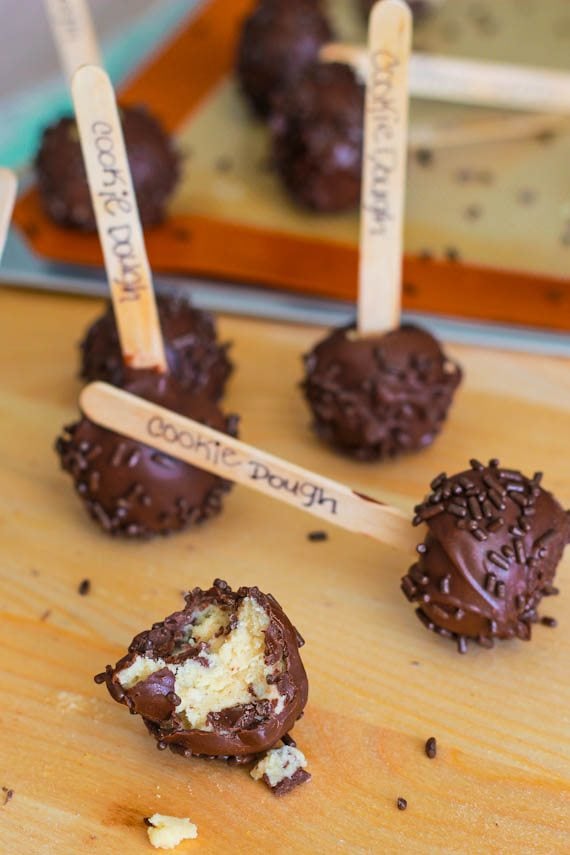 cookie dough covered in chocolate, sprinkles, on a popsicle stick