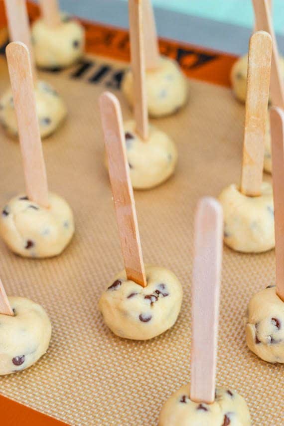 cookie dough balls with a popsicle stick stuck into each