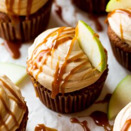 apple spice cupcakes with salted caramel frosting, a drizzle of salted caramel, and a slice of granny smith apple on top