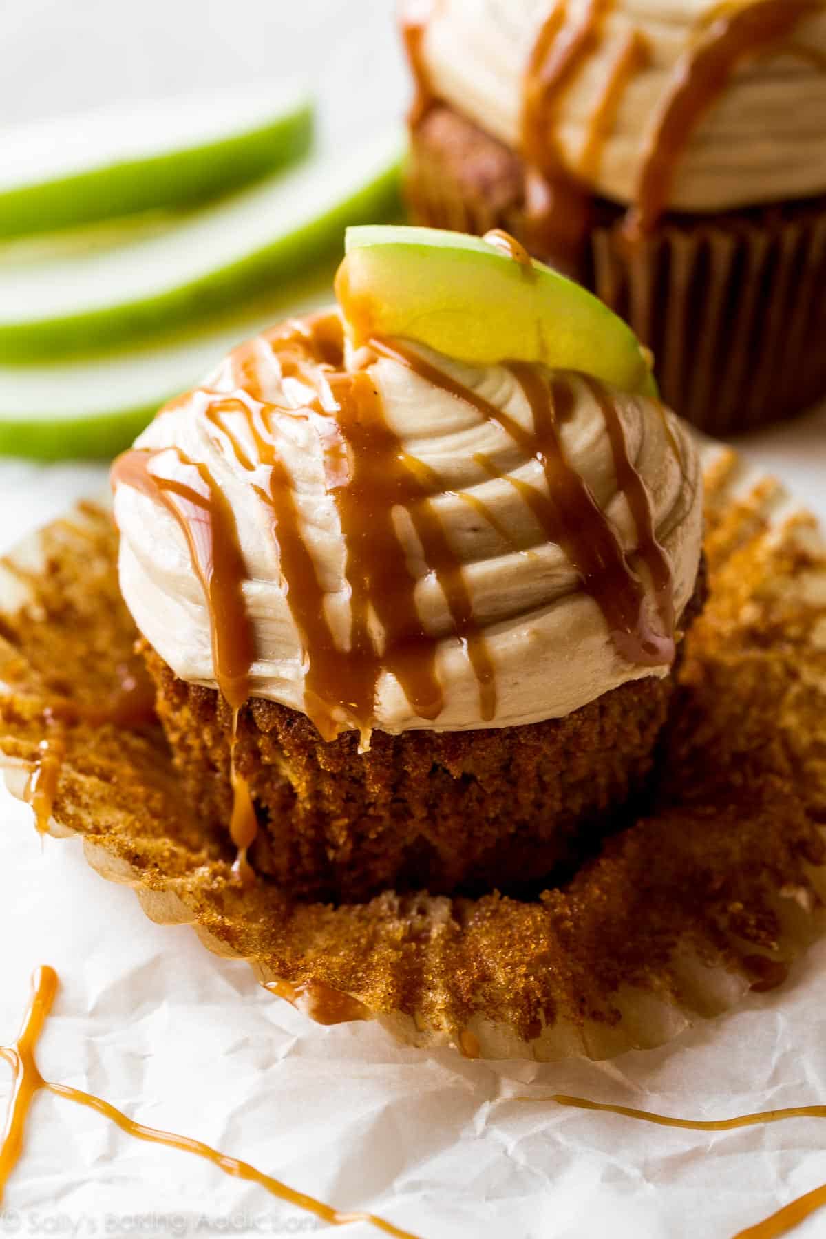 apple spice cupcake with salted caramel frosting, a drizzle of salted caramel, and a slice of granny smith apple on top