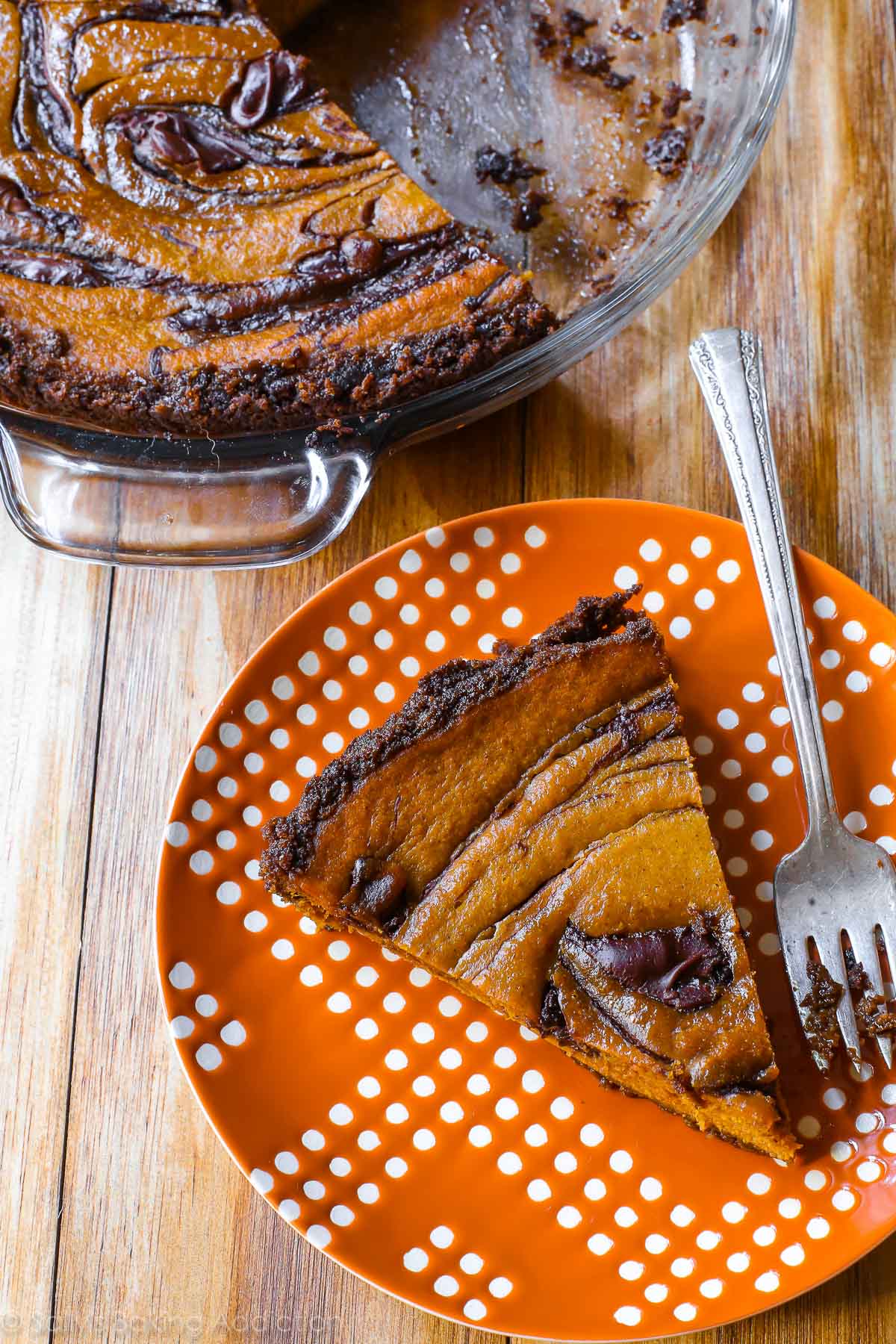 slice of Nutella swirled pumpkin pie on an orange and white plate with a fork