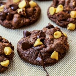 chocolate cookies with chocolate chips and peanut butter chips on a silpat baking mat