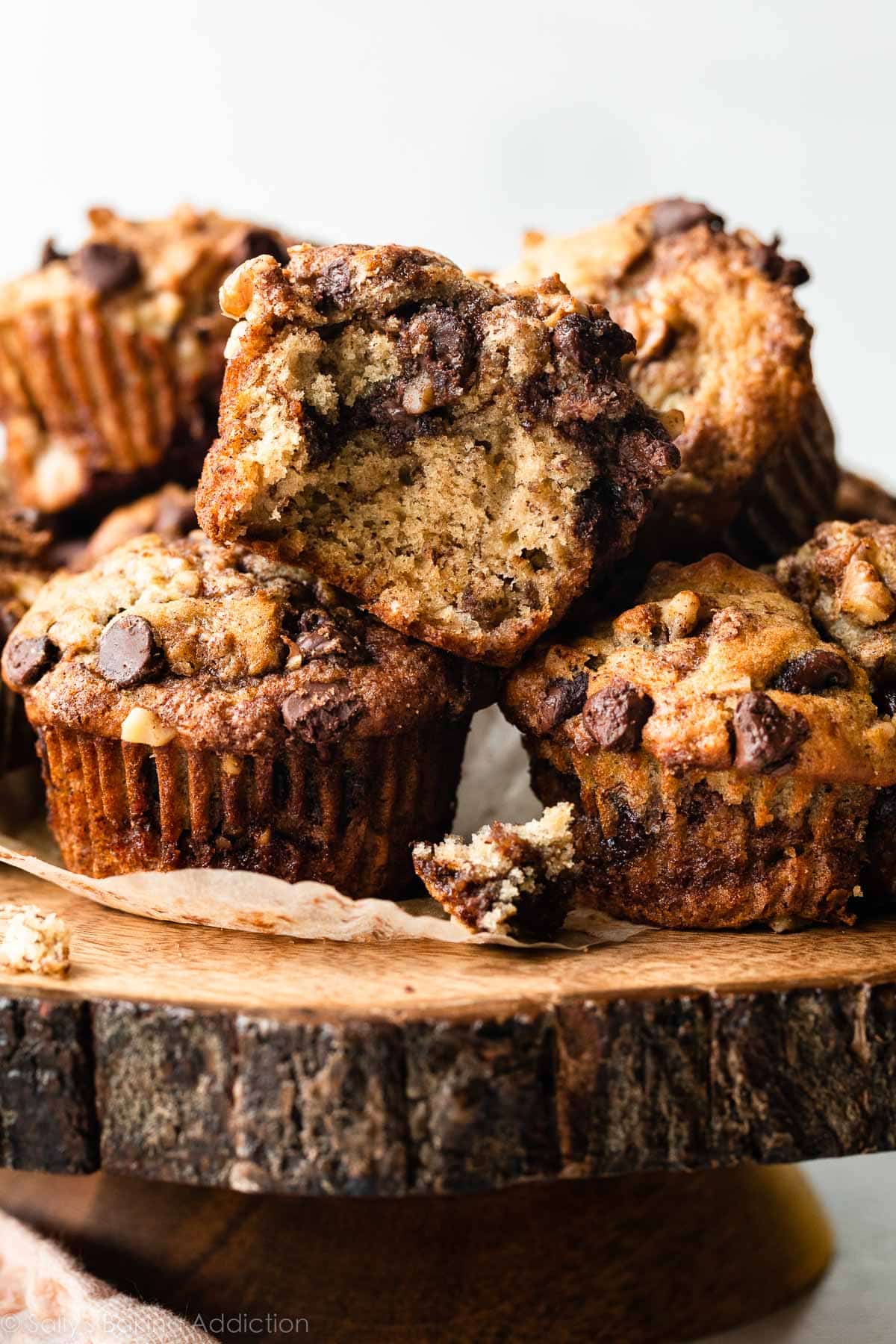 banana muffins with chocolate chip cinnamon streusel piled on wooden cake stand.