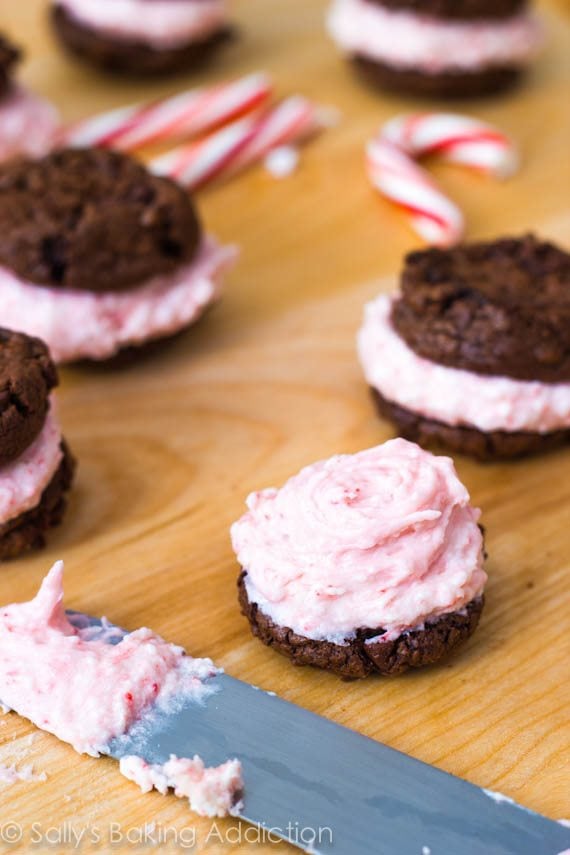 spreading candy cane buttercream onto a chocolate cookie