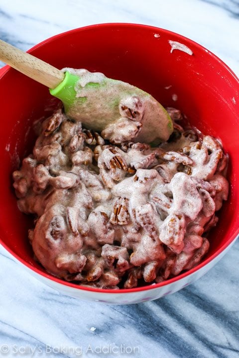 pecans with cinnamon sugar coating in a red bowl with a spatula