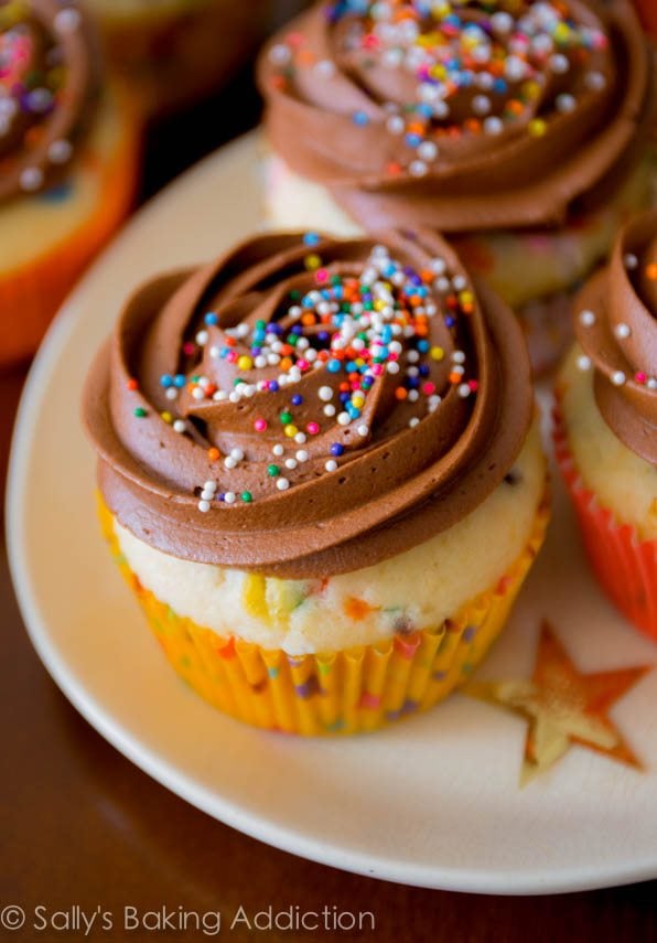 funfetti cupcakes topped with chocolate buttercream and sprinkles on a white plate
