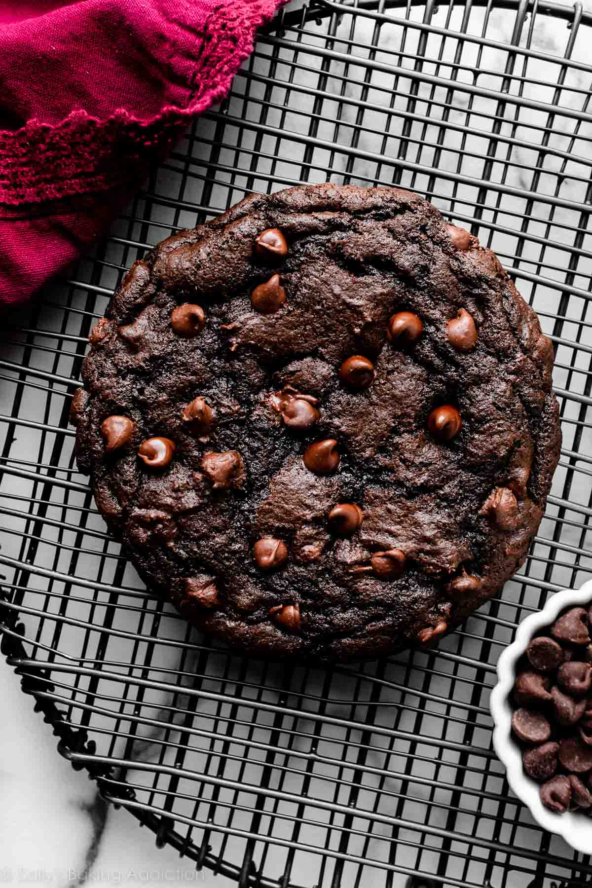 giant double chocolate cookie on round black wire cooling rack.