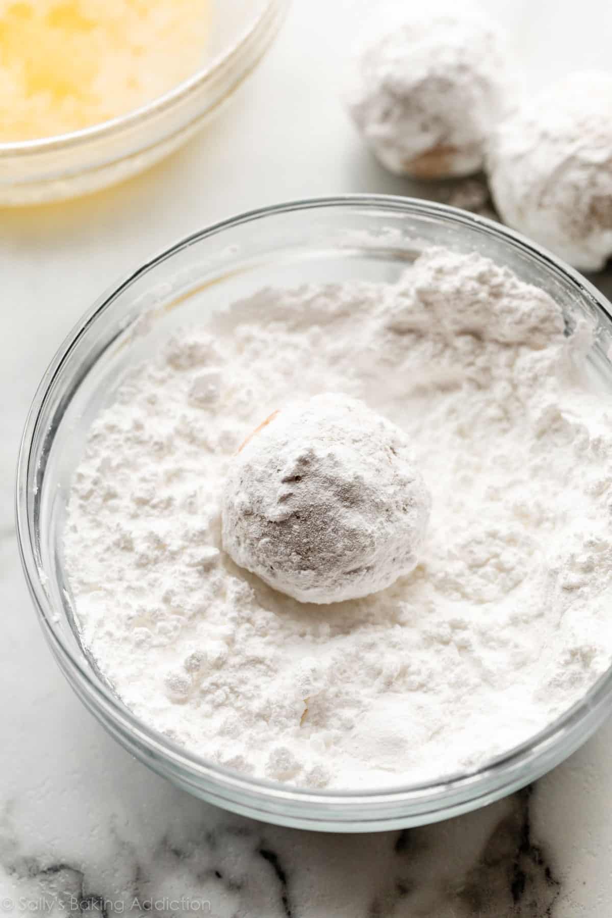 rolling mini donut-style muffin in powdered sugar