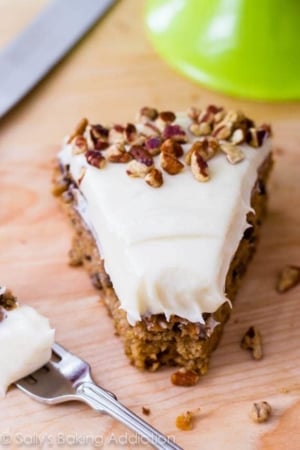 slice of carrot cake topped with cream cheese frosting with a fork