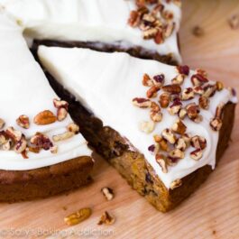 slice of carrot cake topped with cream cheese frosting and chopped pecans