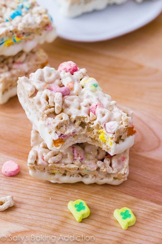 stack of Lucky Charms Treats with the bottoms dipped in white chocolate with a bite taken from one