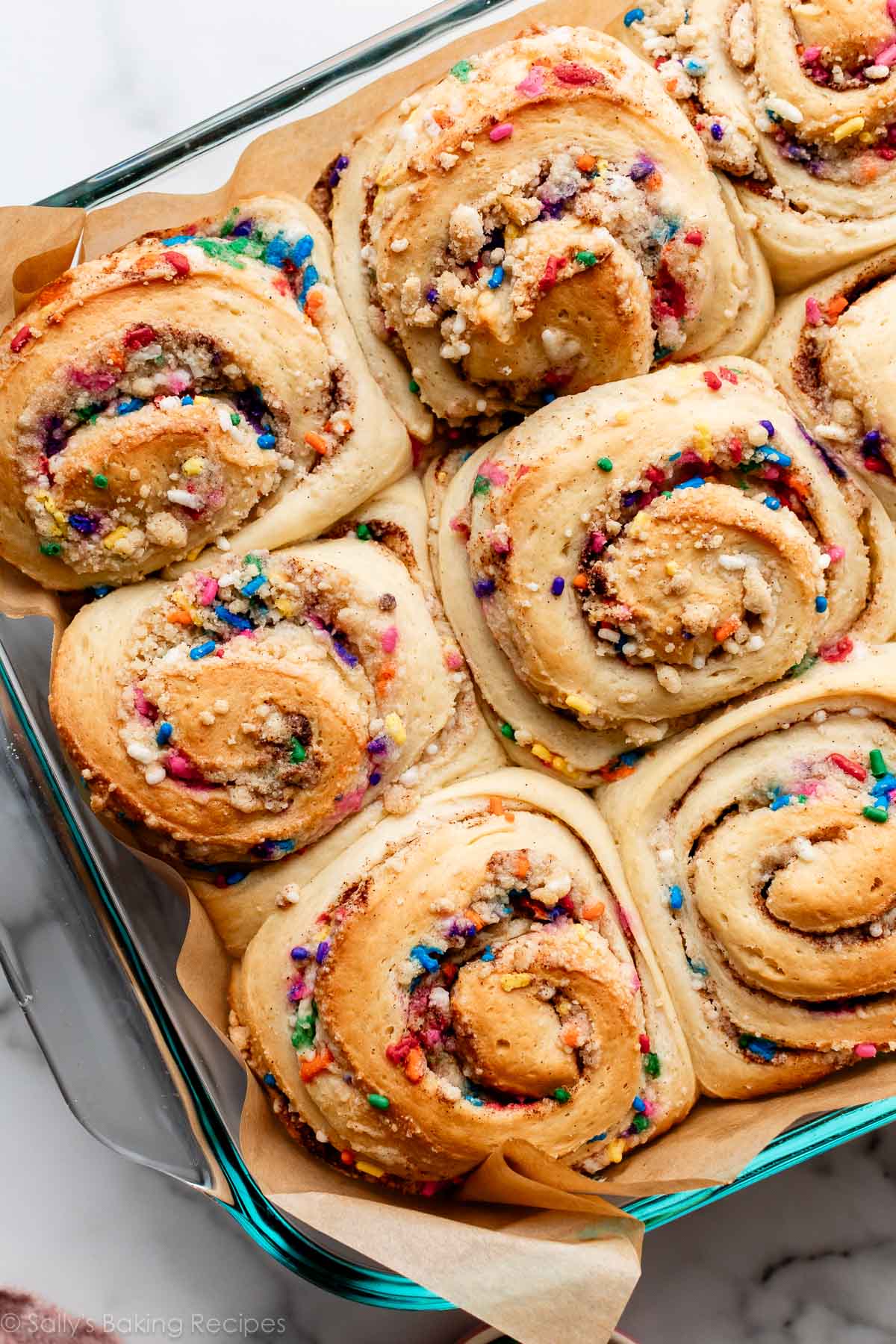 funfetti cinnamon rolls with sprinkles after baking in glass pan.