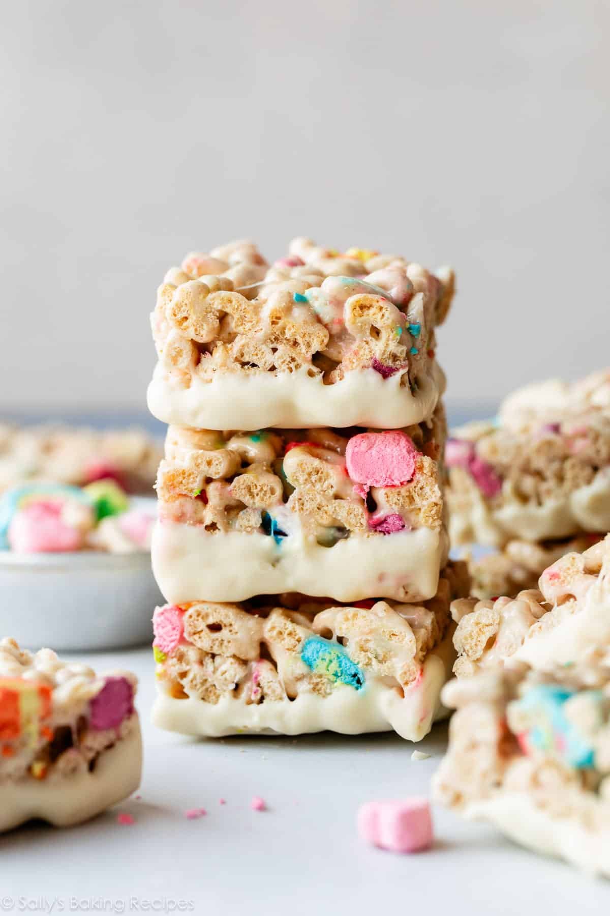 stack of 3 white chocolate dipped Lucky Charms cereal treats.