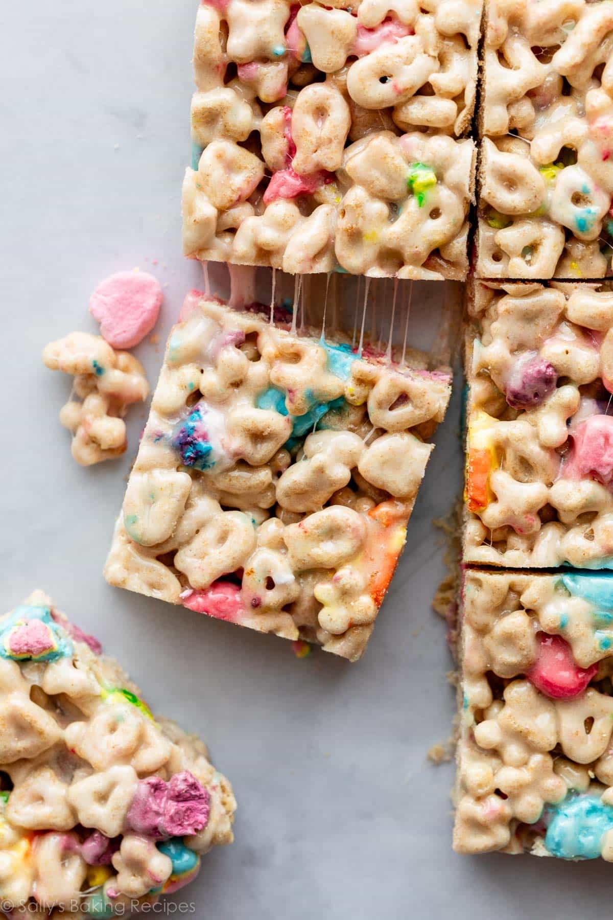 lucky charms marshmallow cereal treats cut into squares on parchment paper.