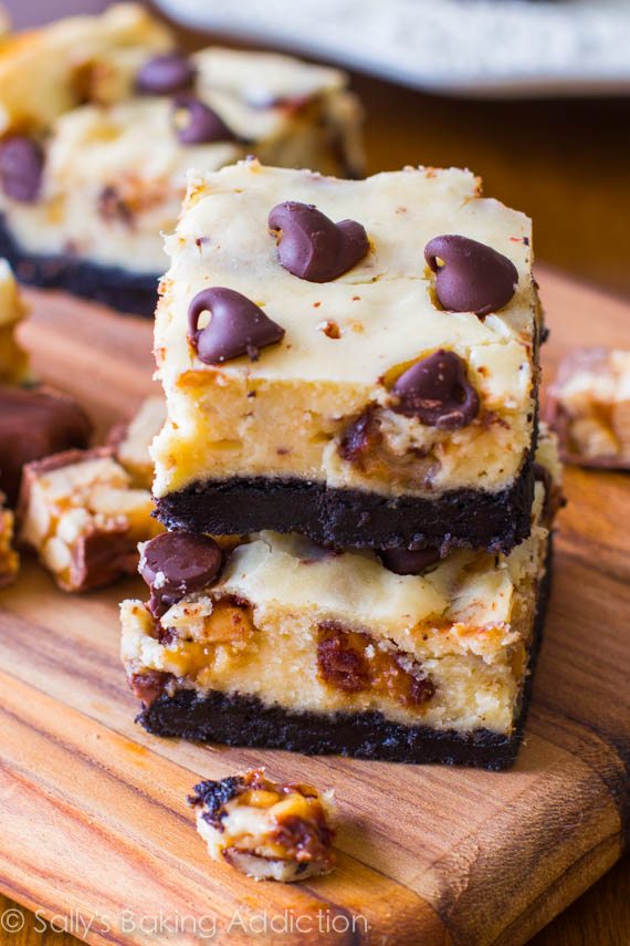 stack of Snickers cheesecake bars on a wood board