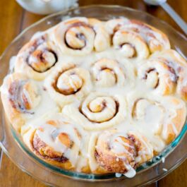cinnamon rolls topped with icing in a glass baking dish