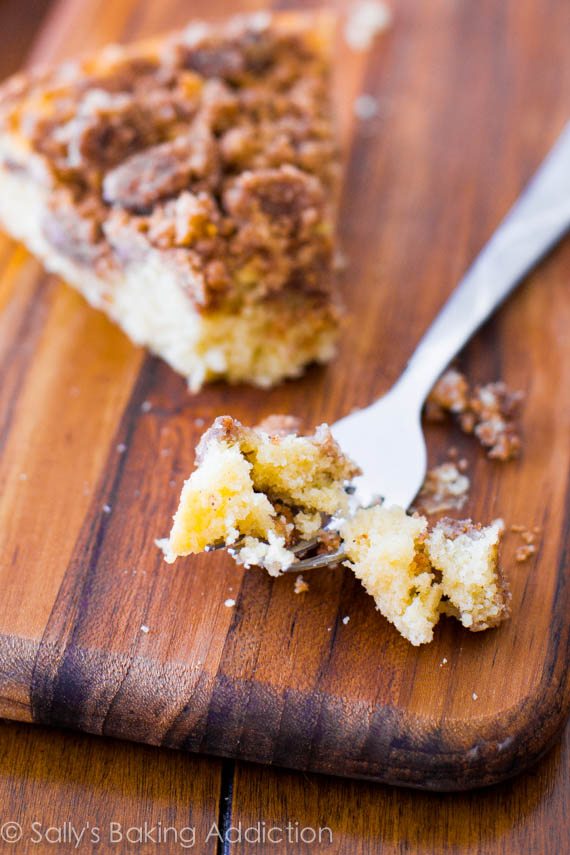 slice of super crumb coffee cake on a wood board with a fork