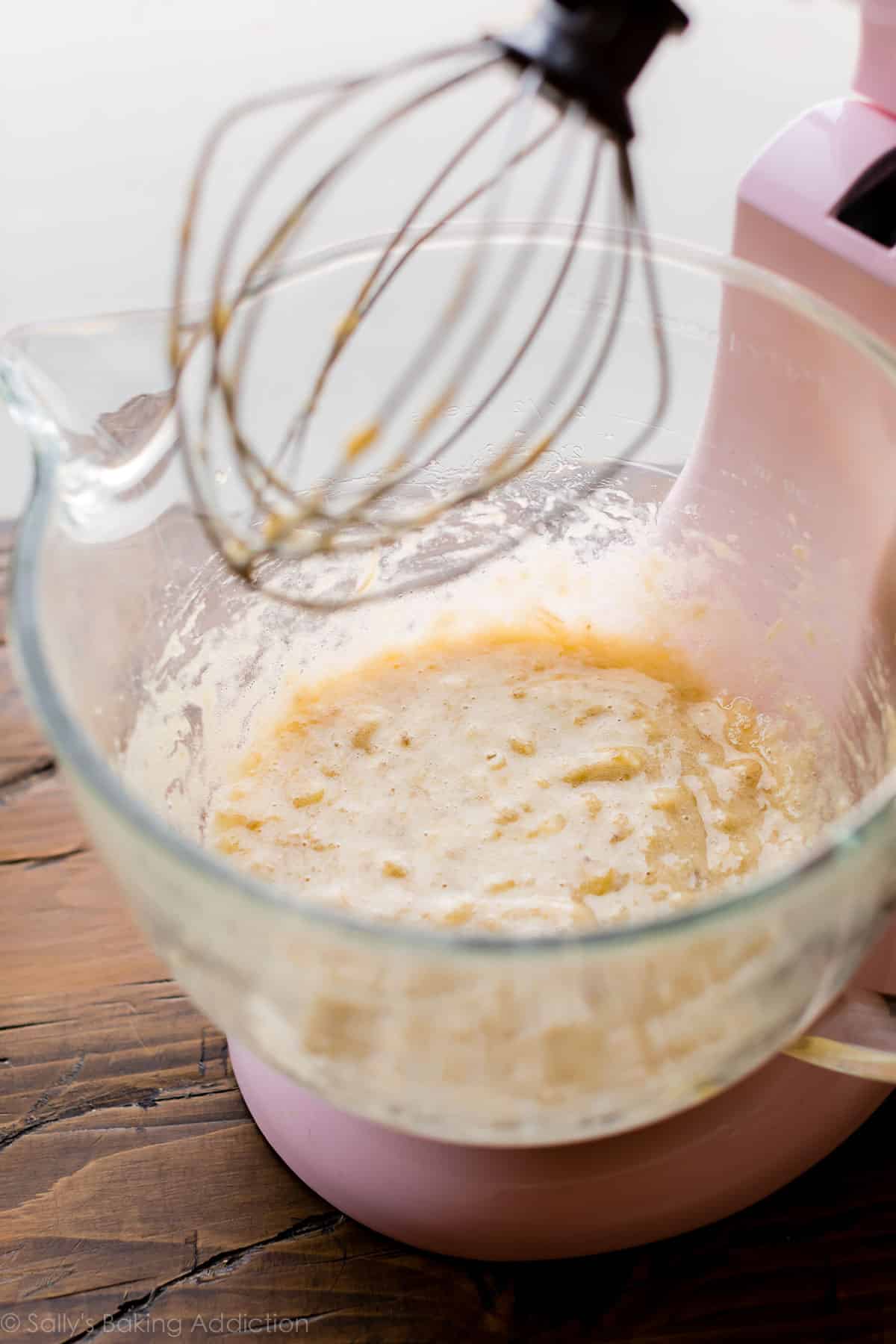 mashed bananas in a stand mixer bowl with whisk attachment