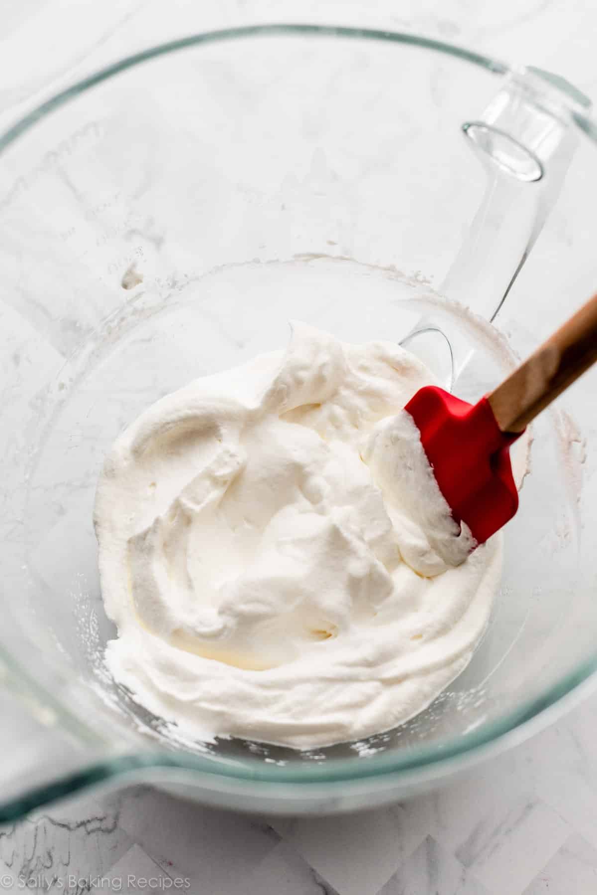 whipped cream and red spatula in glass bowl.