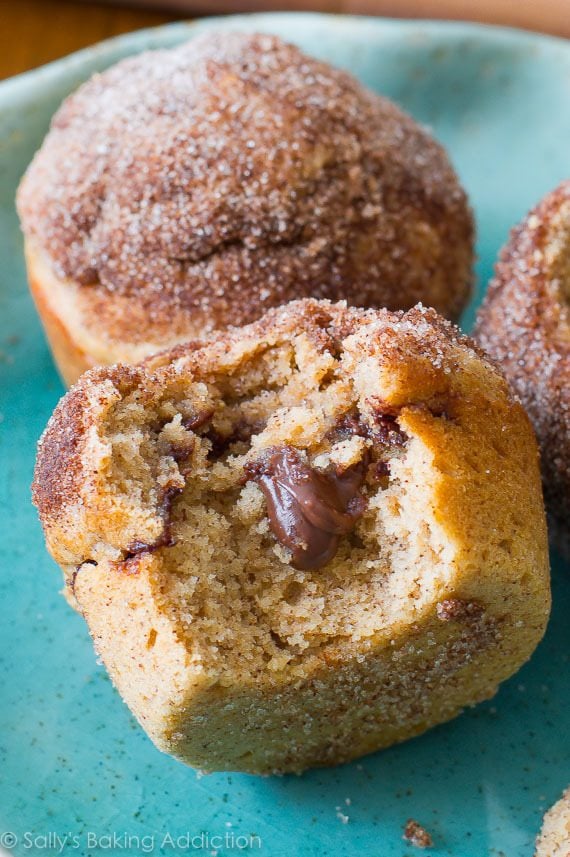 cinnamon sugar muffins stuffed with Nutella with a bite taken out of one showing the middle on a blue plate