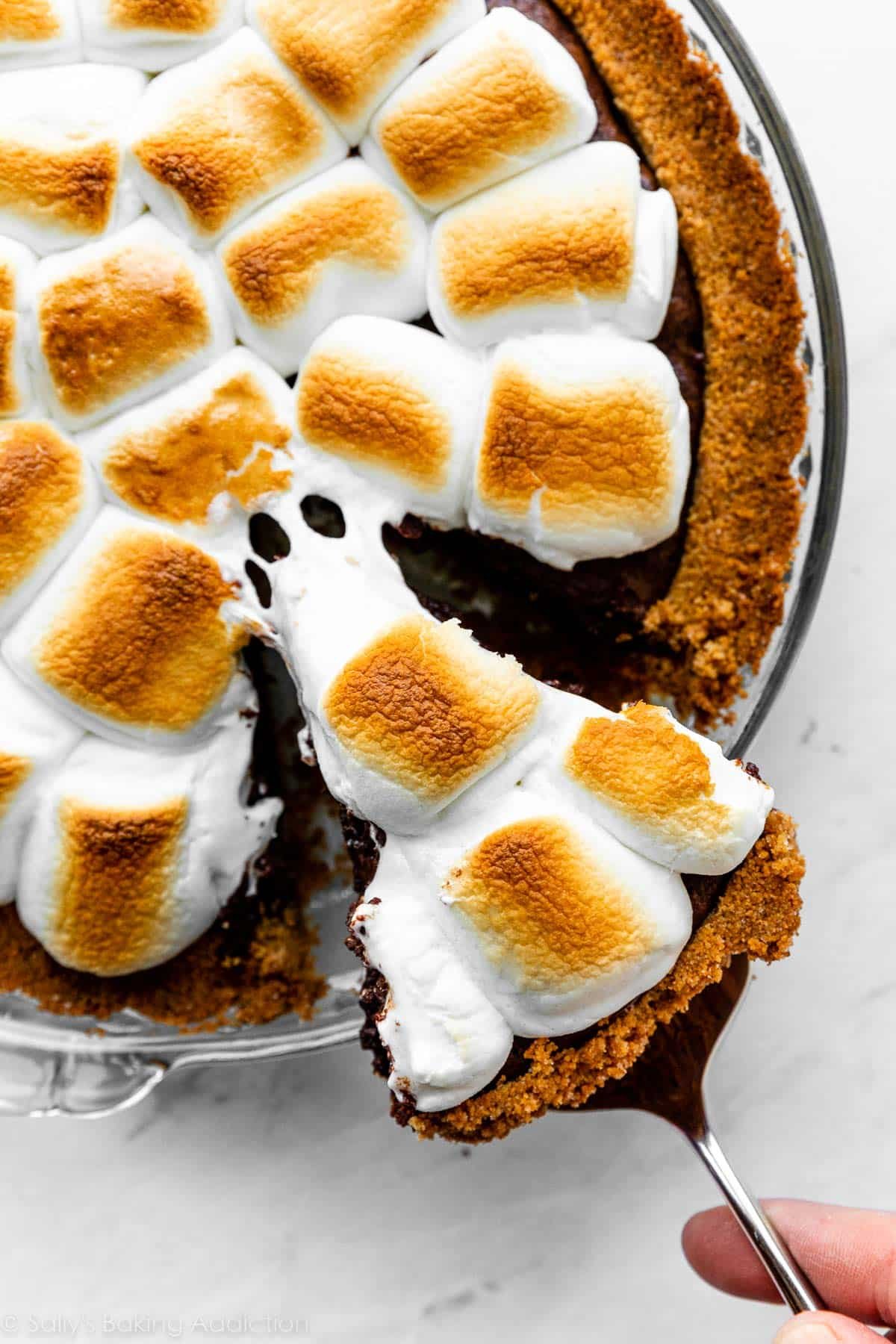 pulling slice of marshmallow s'mores pie out of pie dish.