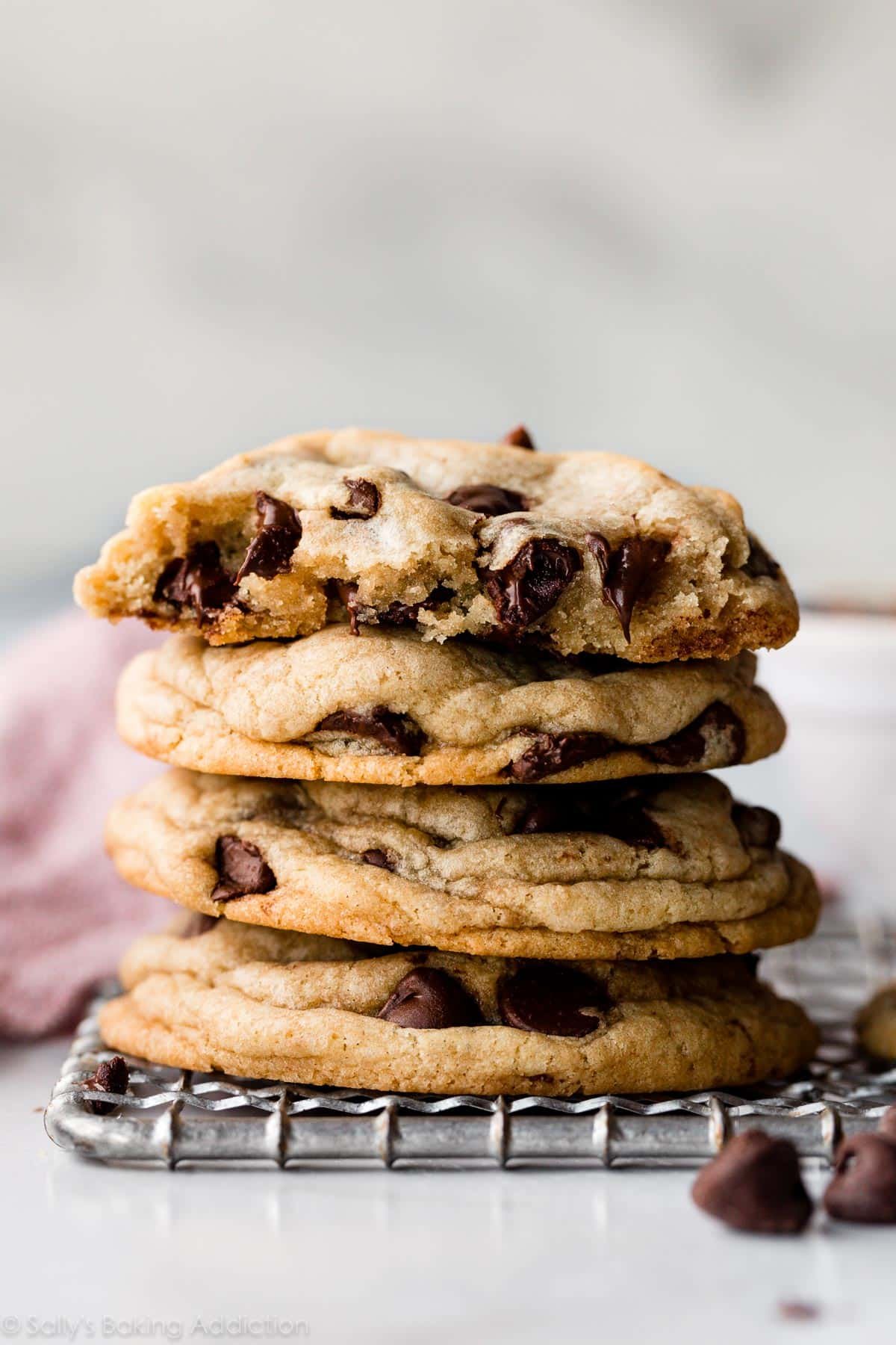 A stack of 4 chocolate chip cookies with the top biscuit cut in half