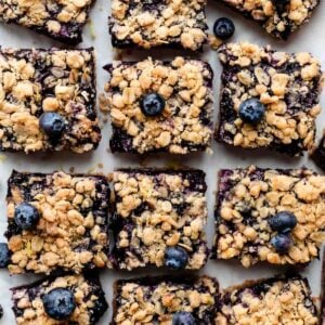 overhead photo of blueberry bars with crumble topping arranged on parchment paper.