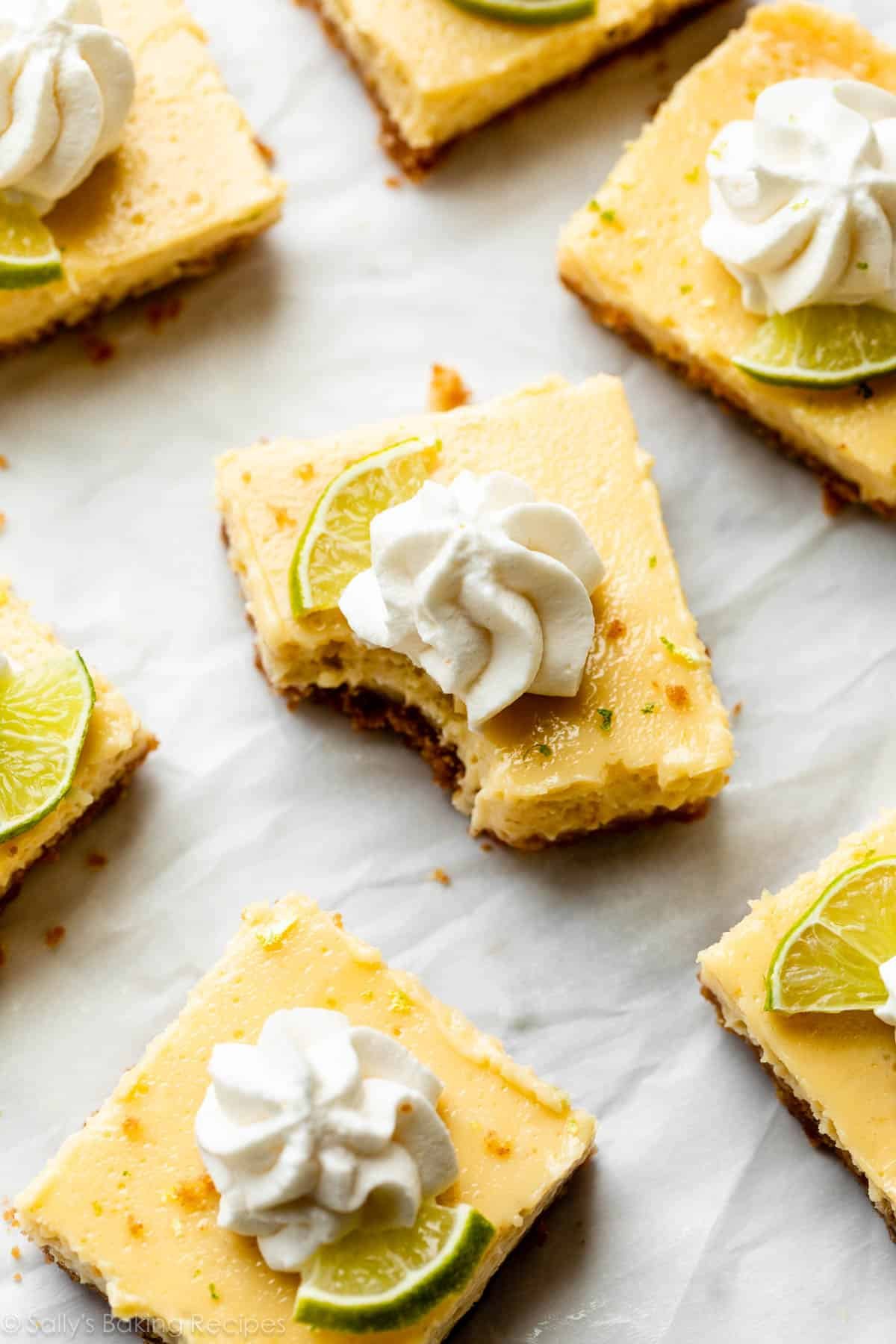 key lime pie bars with piped whipped cream and lime slices on top.