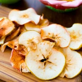 baked cinnamon apple chips on a wood board