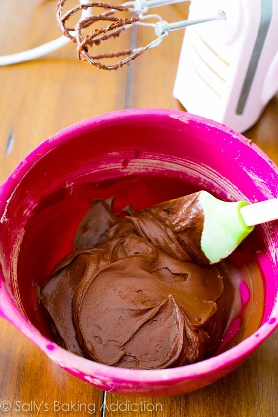dark chocolate frosting in a pink bowl with a spatula