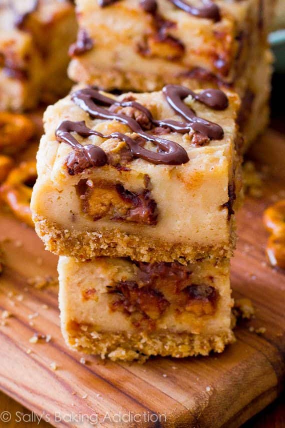 stack of peanut butter cup pretzel cheesecake bars on a wood board