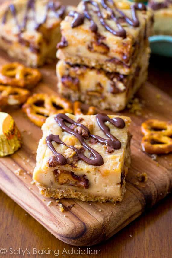 peanut butter cup pretzel cheesecake bars on a wood board