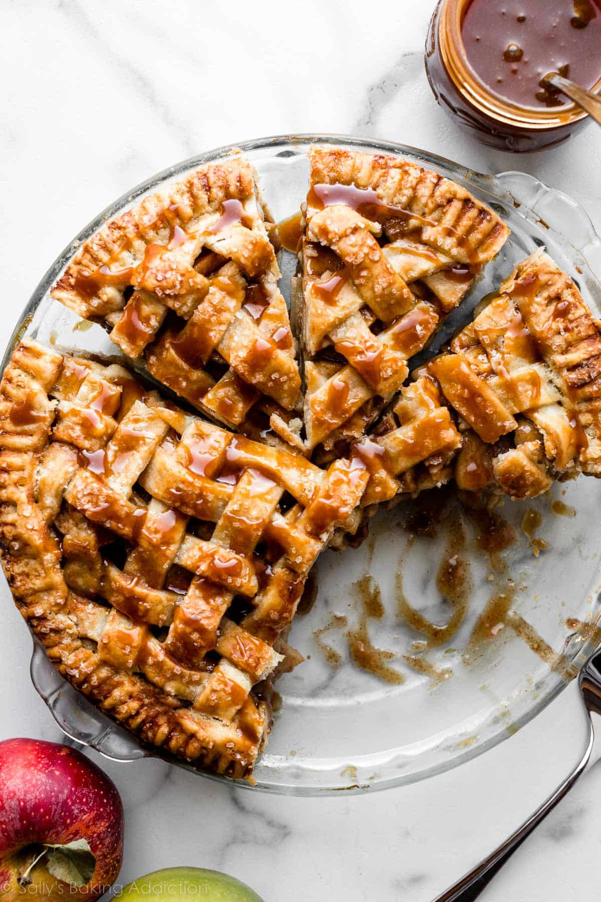 overhead photo of a salted caramel apple pie with lattice pie crust in a glass pie dish.