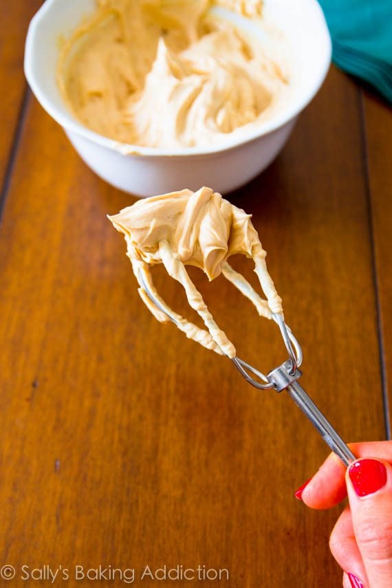 hand holding a beater with Greek yogurt peanut butter frosting on it
