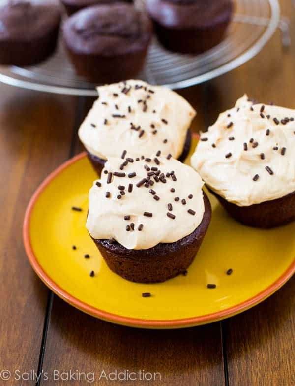 chocolate cupcakes topped with peanut butter Greek yogurt frosting and chocolate sprinkles on a yellow plate