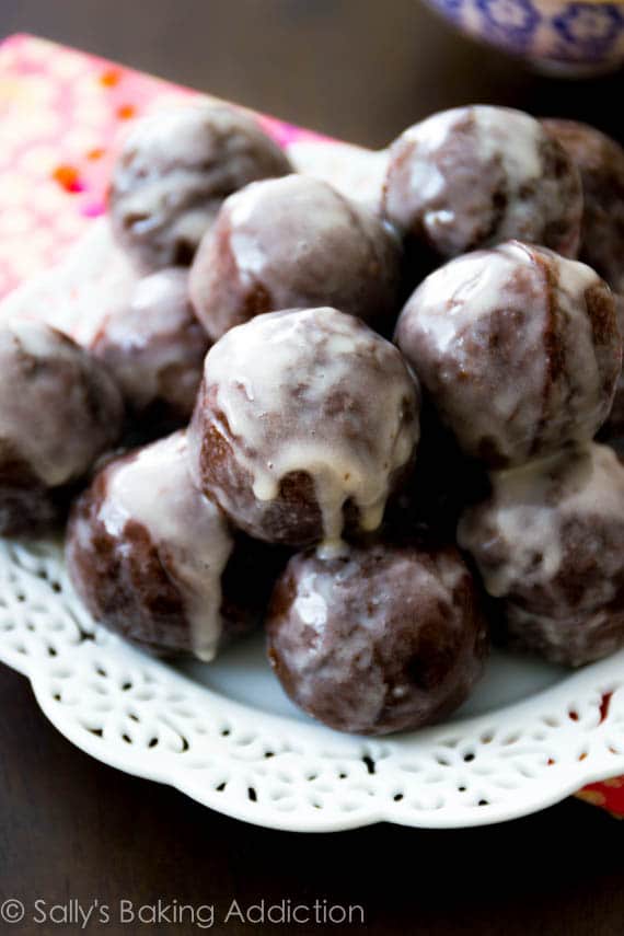stack of glazed chocolate donut holes on a white plate