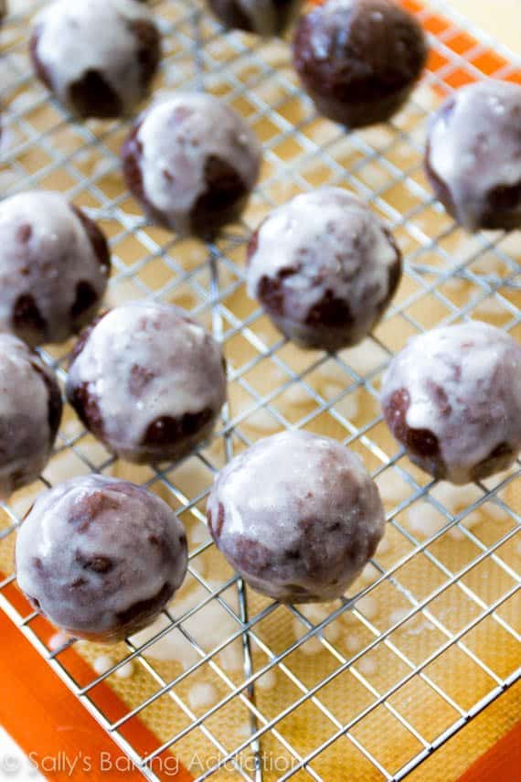glazed chocolate donut holes on a cooling rack