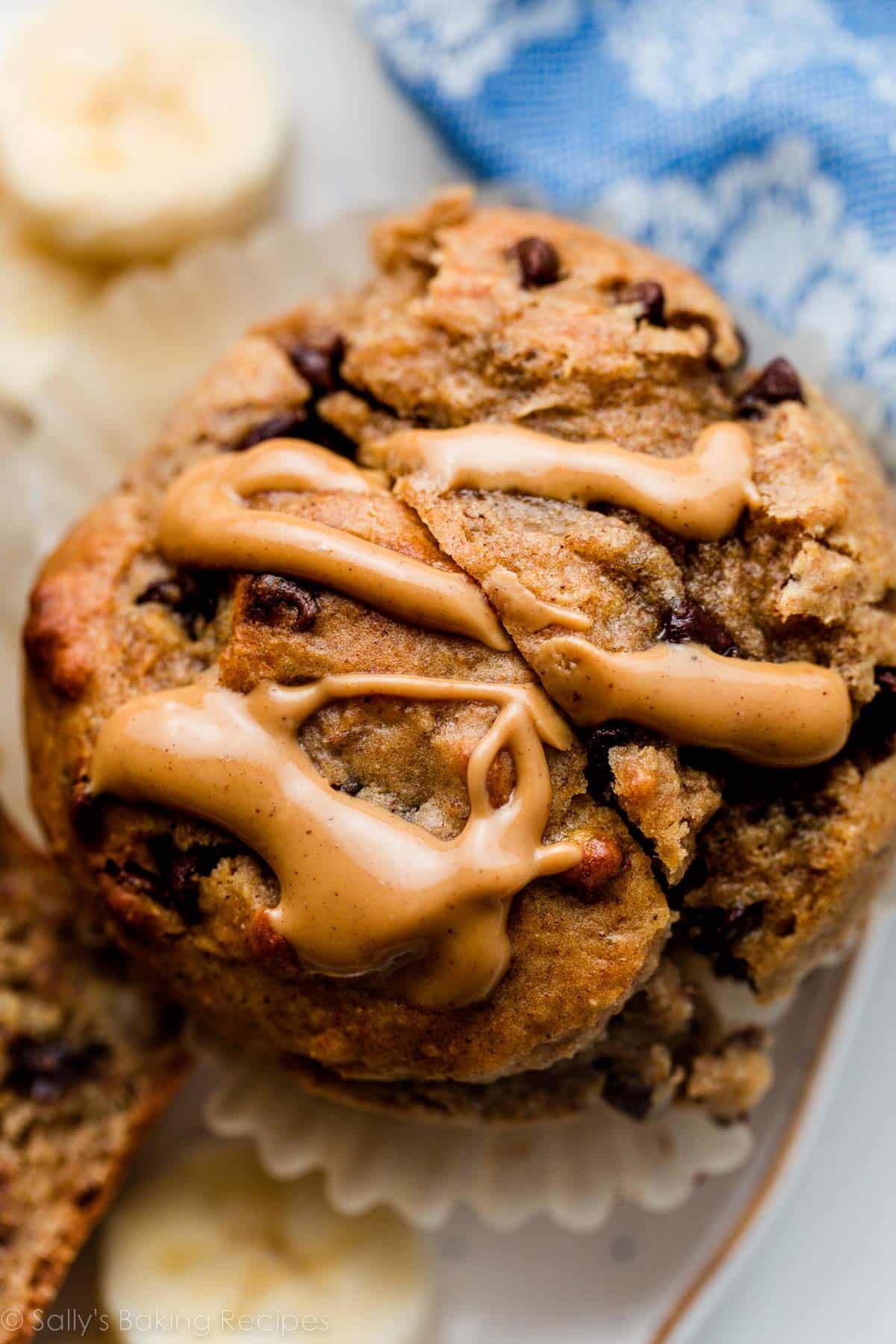 close up photo of banana chocolate chip muffin with melted peanut butter drizzled on top.