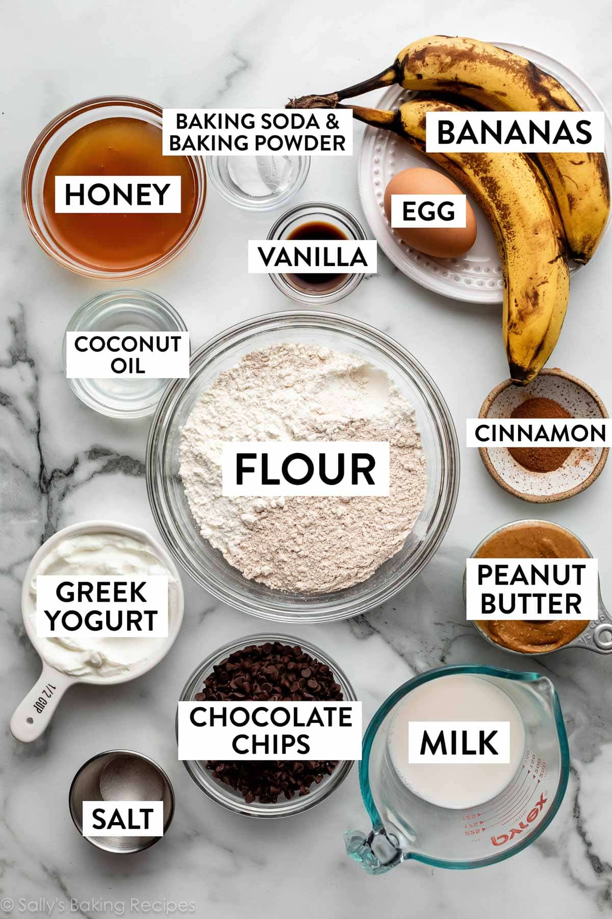 ingredients on marble backdrop including bananas, honey, flour, milk, peanut butter, greek yogurt, and more.