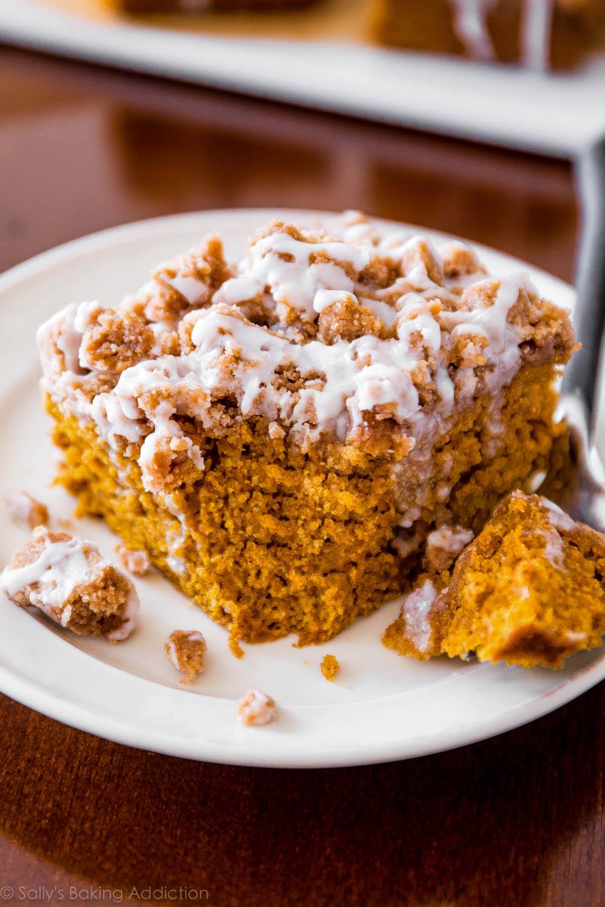 slice of iced pumpkin coffee cake on a white plate with a fork