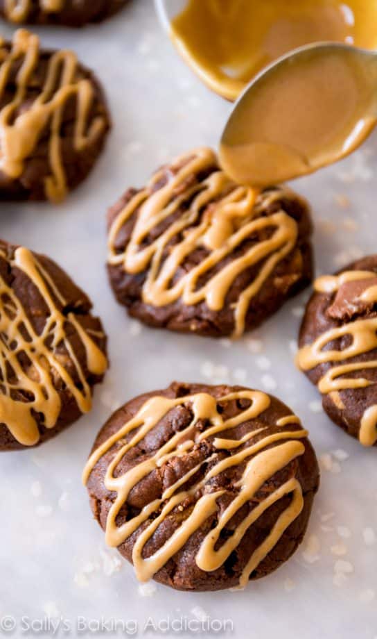 using a spoon to drizzle peanut butter onto chocolate cookies