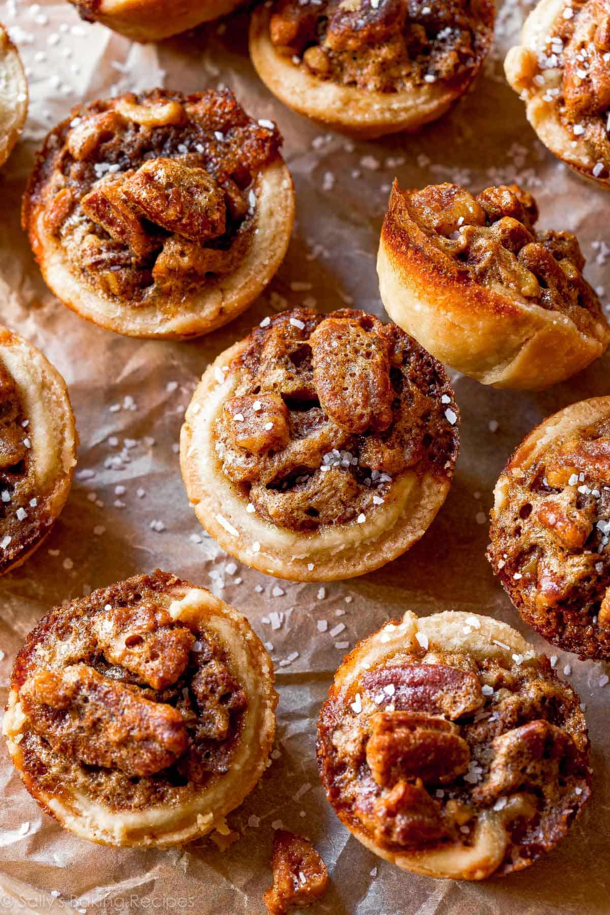 mini pecan pies with salt on top on brown parchment paper.