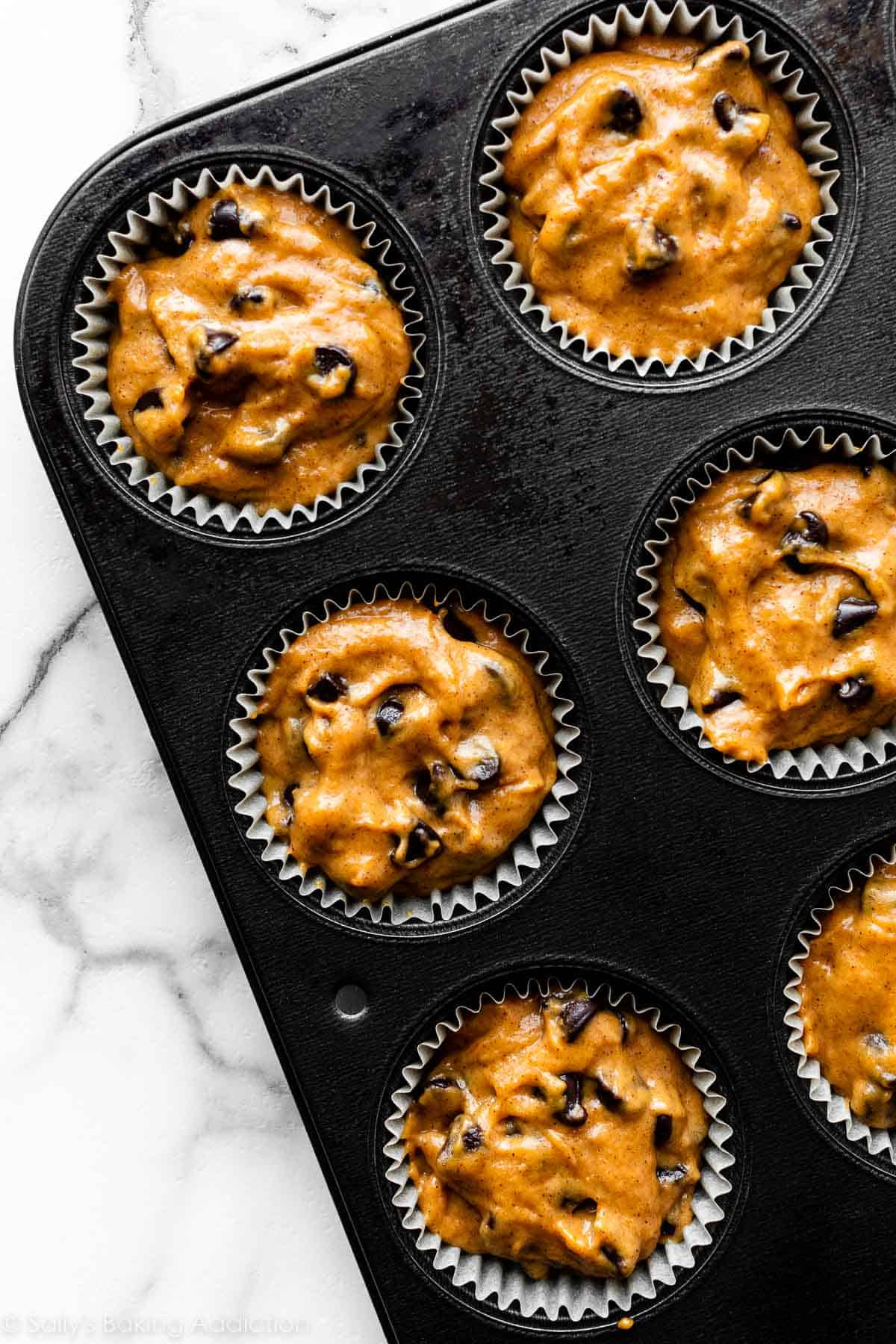 pumpkin batter with chocolate chips in muffin pan.
