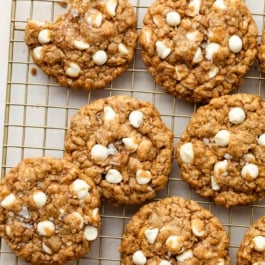Biscoff white chocolate oatmeal cookies on a cooling rack with a bite taken out of one cookie.