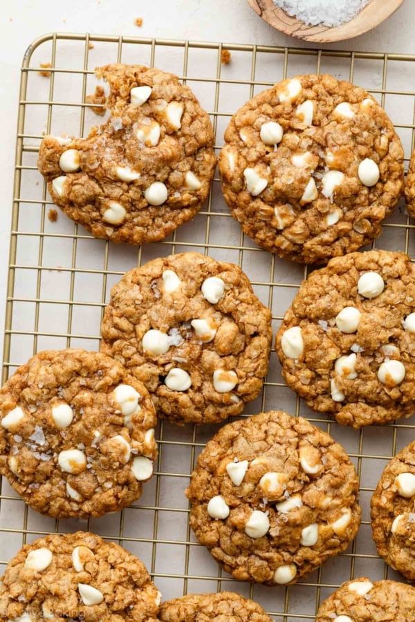 Biscoff white chocolate oatmeal cookies on a cooling rack with a bite taken out of one cookie.